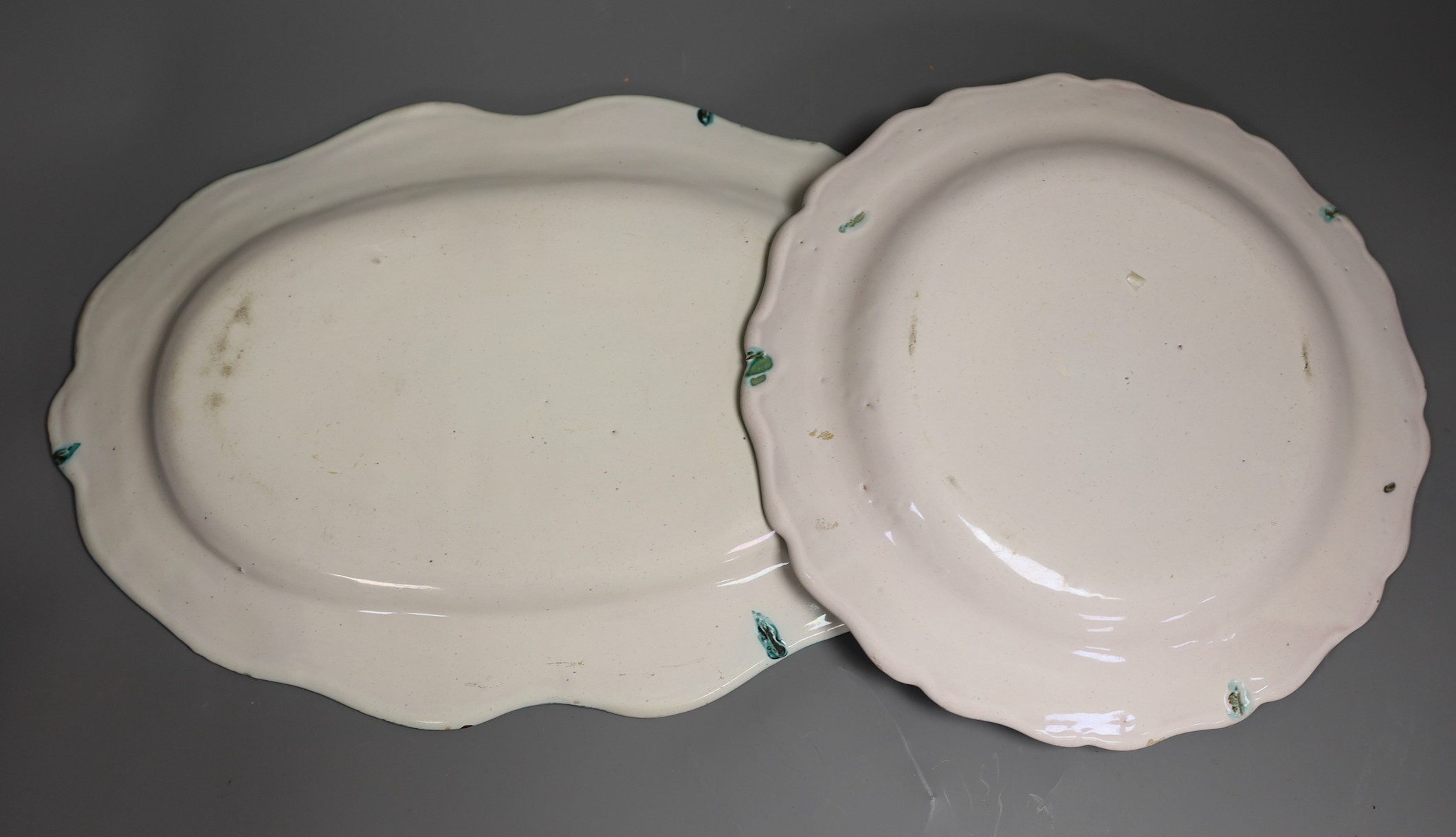 An 18th century French faience green camaieu oval serving dish and a similar plate, largest 36cm